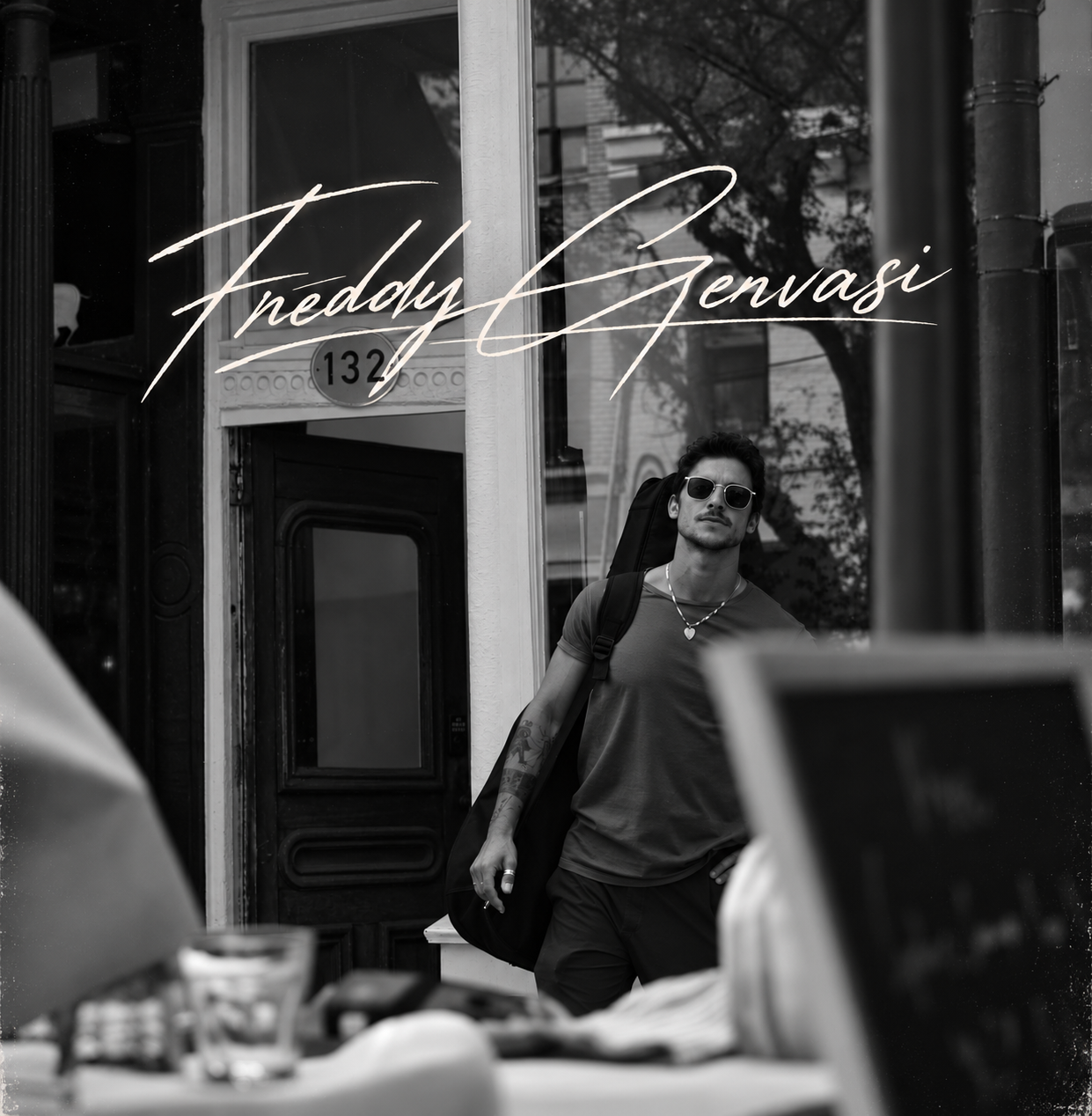 Freddy carrying his guitar past a storefront